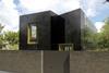 The timber-framed house is clad in black ceramic to give it a high-gloss, reflective surface.