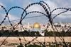 A history of division and conflict: The Old City of Jerusalem, including the Dome of the Rock, seen through coils of razor wire. 